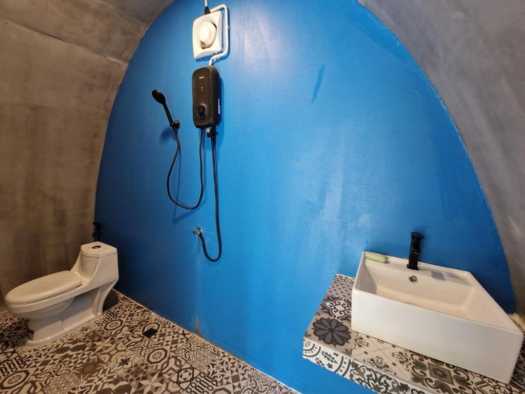 ein blaues Badezimmer mit Toilette und Waschbecken in der Unterkunft The Bear Bungalow in Kampot