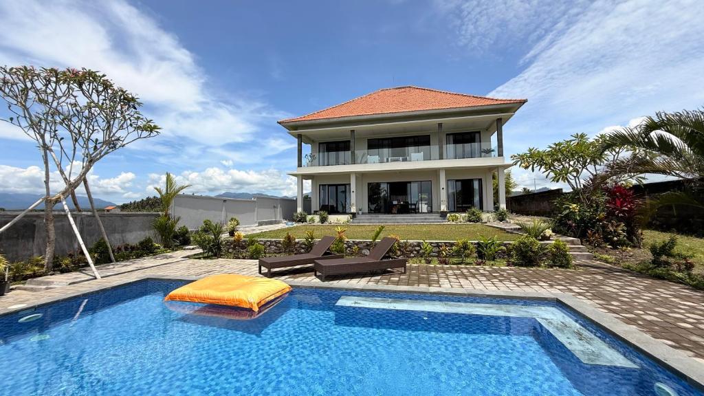 a house with a swimming pool in front of a house at Ocean Daze Villa Yehsumbul in Jembrana