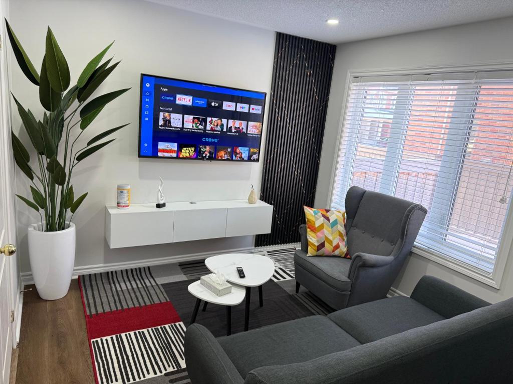a living room with a couch and a chair and a tv at Cozy Private Two-Level Suite In Brampton With Separate Entrance And Living Area on Main Floor in Brampton