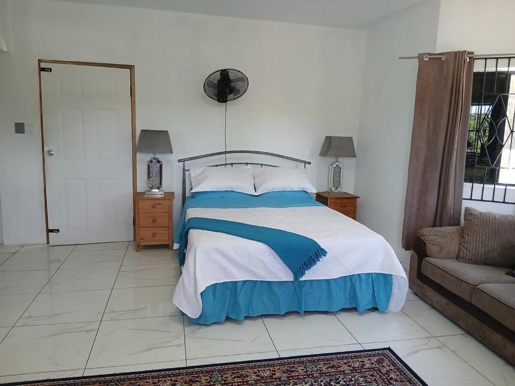 a bedroom with a bed and a couch at Cambridge Heights Guest House in Port Maria
