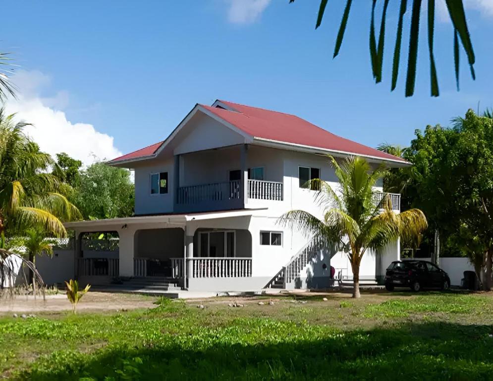 een wit huis met een rood dak bij Trwa Koko Self-catering in Grand'Anse Praslin