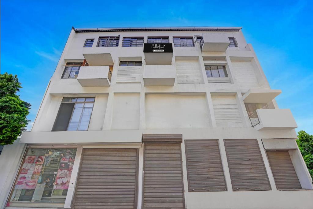 a tall white building with shuttered windows at Collection O Dandiya Bazar Formerly Vrundavan Residency in Vadodara