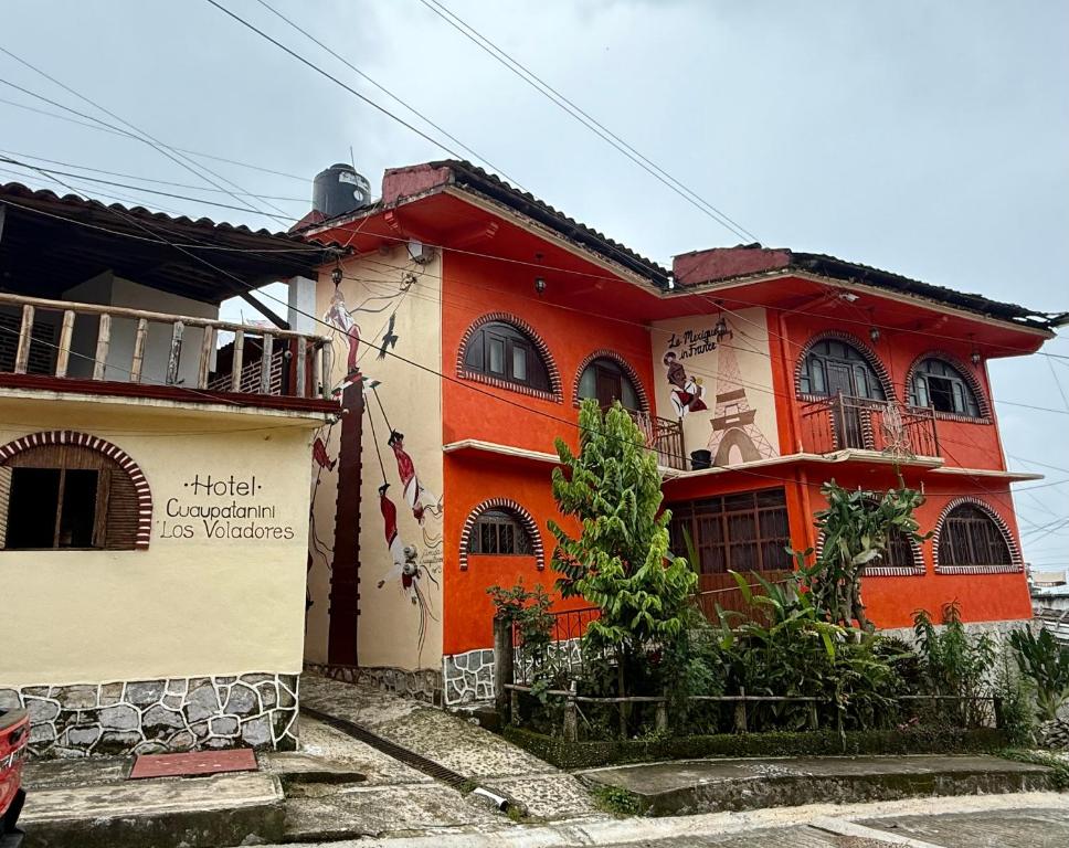 ein orangefarbenes und weißes Gebäude mit einem Schild darauf in der Unterkunft Hotel Cuaupatanini in Xocoyolo
