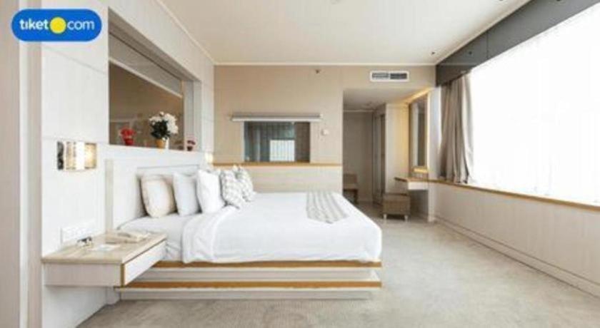 a bedroom with a white bed and a large window at Horison Ultima Makassar in Makassar