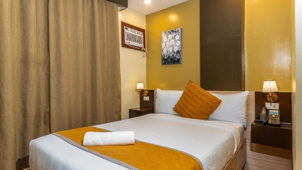 una camera da letto con un grande letto con pareti gialle di Hollywood Hotel Puerto Princesa a Città di Puerto Princesa