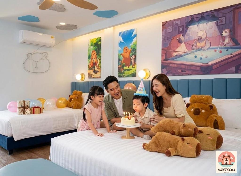una famiglia seduta sui letti con una torta di compleanno di Casa de Capybara a Siem Reap