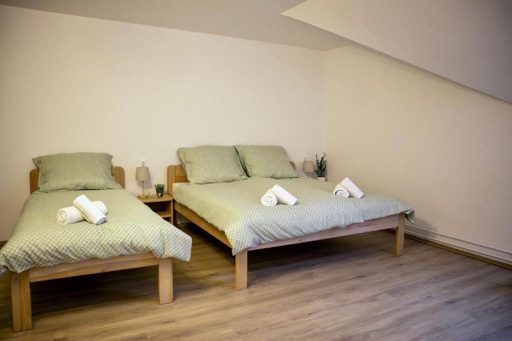 two twin beds in a room with wooden floors at Ízisz Apartman in Mátraterenye