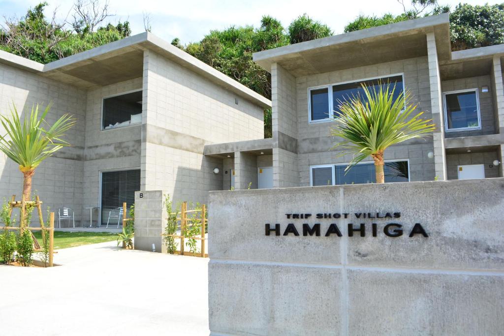 een gebouw met palmbomen ervoor bij Trip Shot Villas Hamahiga in Uruma