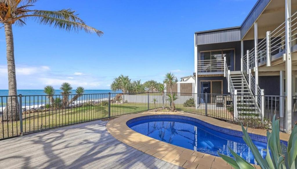 a house with a swimming pool next to the ocean at Driftwood in Bargara