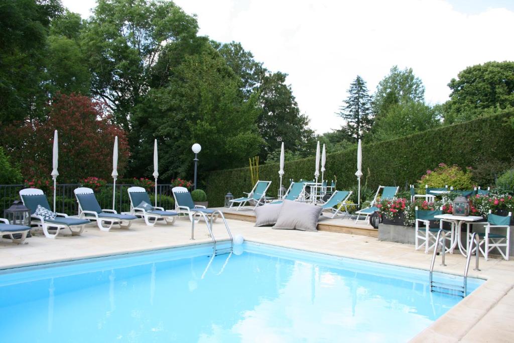 einen Pool mit blauen Stühlen sowie einem Tisch und Stühlen in der Unterkunft Logis Hôtel Auberge de L'Etang in Magnac-Bourg