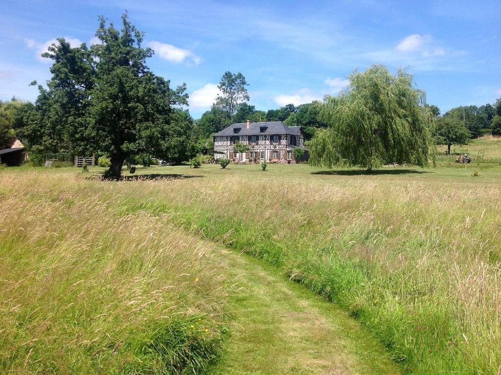 een veld van hoog gras met een huis op de achtergrond bij L'Orchard in Bonneville-la-Louvet