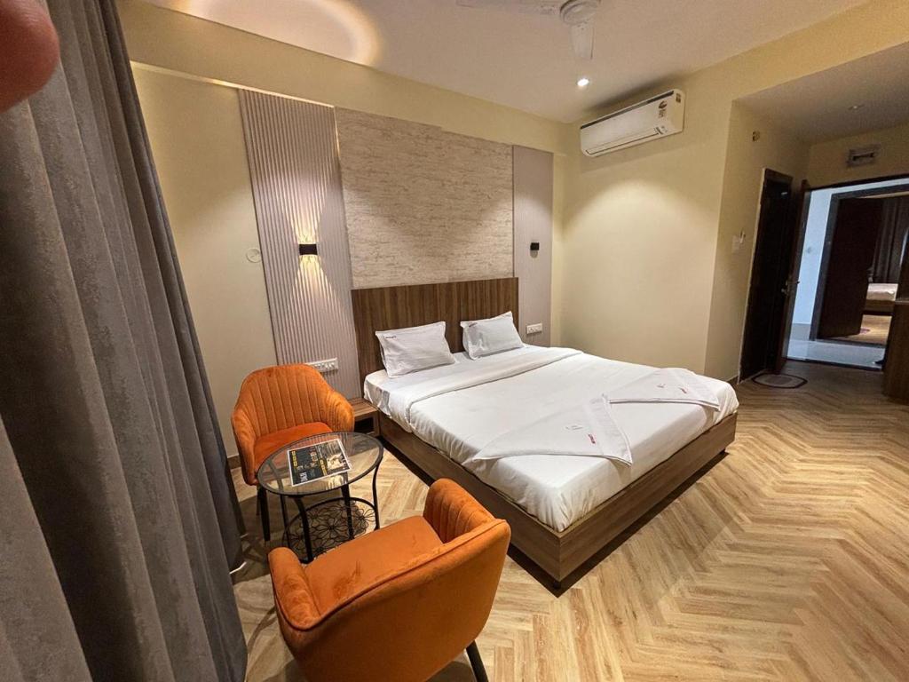 a hotel room with a bed and two chairs at Hotel Nirmal's Executive in Pune
