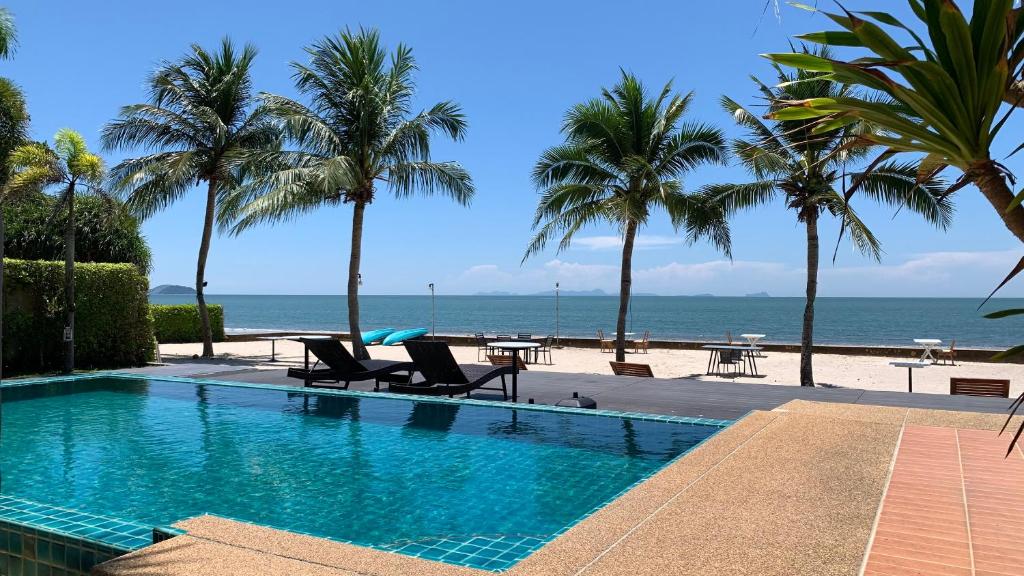 a swimming pool next to a beach with palm trees at Purin Resort & Restaurant- SHA Plus in Had Yao Beach