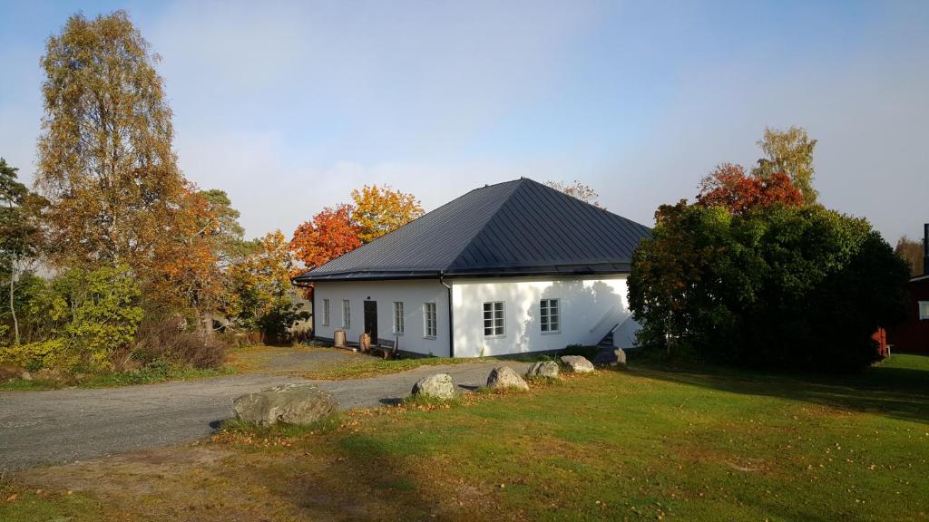 une petite maison blanche avec un toit noir dans l'établissement Bjärkas Golf & Country Club, à Nivelax