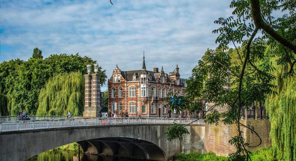 a bridge over a river in front of a large building at Bossche Suites Stationsweg in Den Bosch