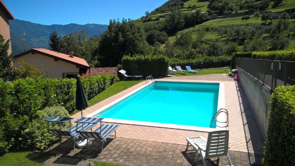 einen Pool mit zwei Stühlen und ein Haus in der Unterkunft Un Angolo di Relax in Tavernola Bergamasca