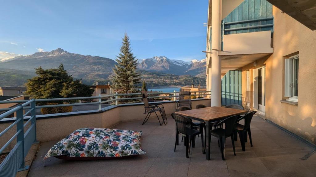 een balkon met een tafel en stoelen en bergen bij Studio with large terrace and view in Savines