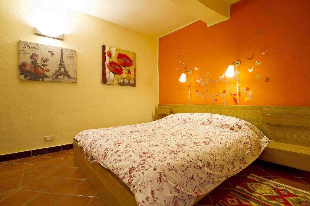 ein Schlafzimmer mit einem Bett mit einer orangefarbenen Wand in der Unterkunft Camera Dolcenotte in Orta San Giulio