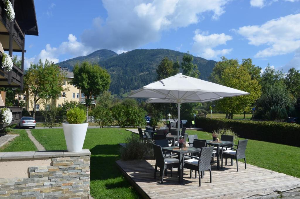 eine Terrasse mit Tischen, Stühlen und einem Sonnenschirm in der Unterkunft Dahoam by Sarina - Rooms & Suites in Zell am See