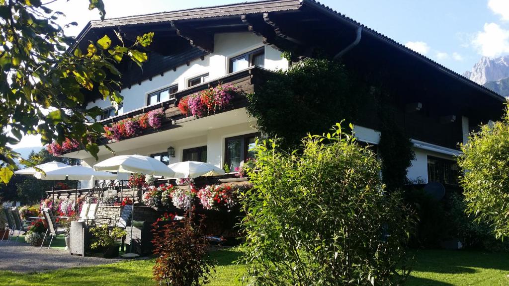 a building with umbrellas and flowers in front of it at Bergschlößl in Ramsau am Dachstein