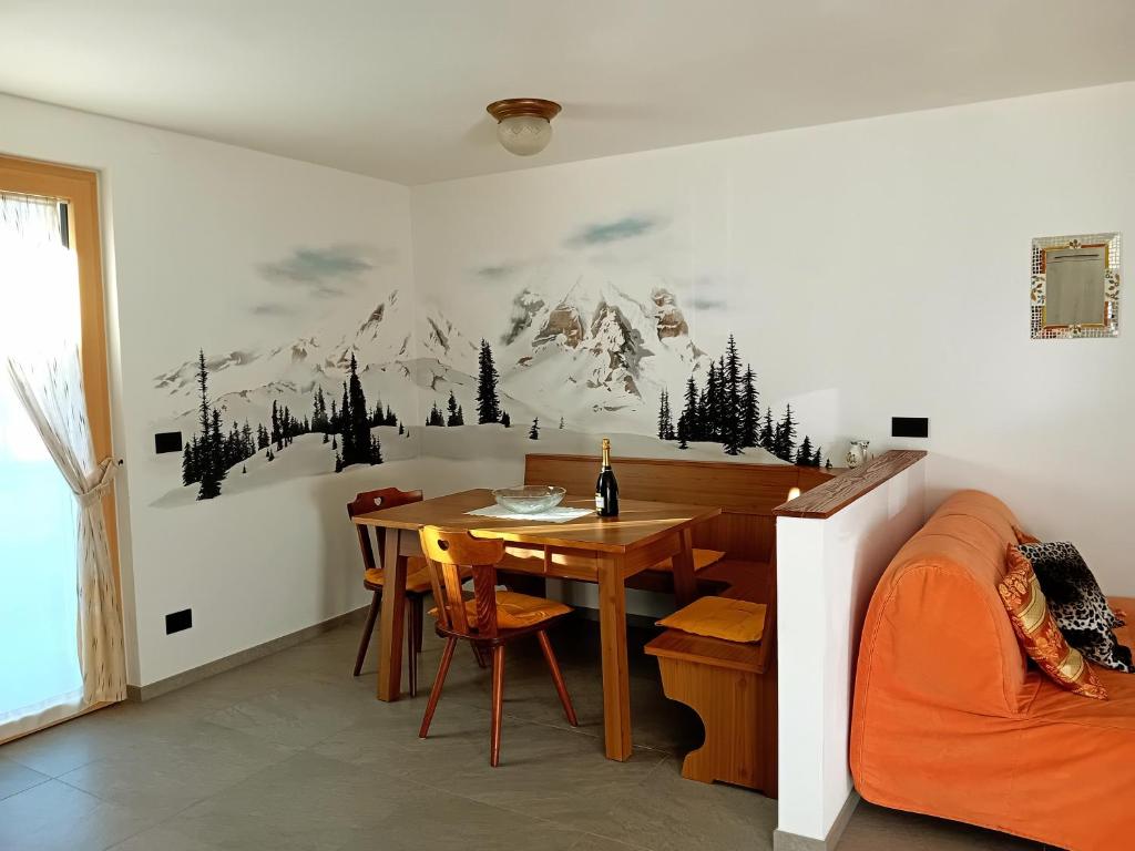 a dining room with a table and a mountain mural on the wall at Appartamento Miele di Pino in Ziano di Fiemme