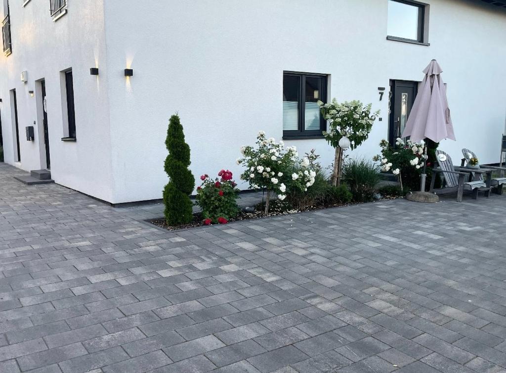 a patio with an umbrella and flowers in front of a building at Ferienwohnung in der wunderschönen Eifel in Dankerath