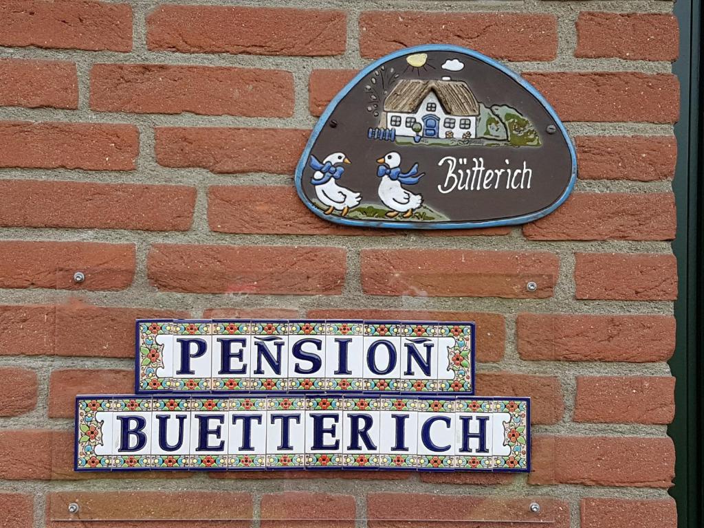 um sinal na parede de uma parede de tijolos em Pension Bütterich em Husum