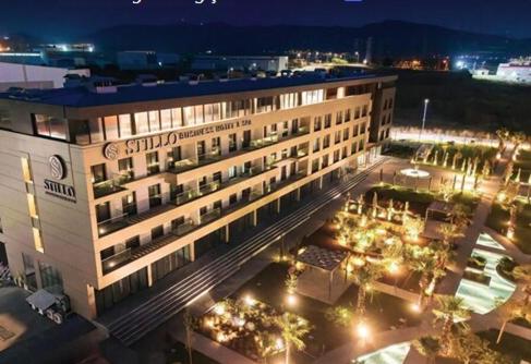 a large building with lights in a courtyard at night at Stillo Business Hotel & Spa in Aliağa