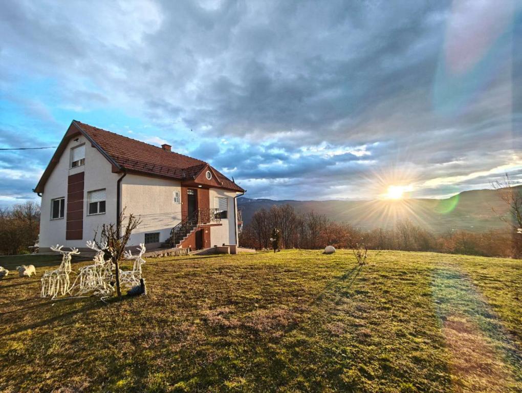 una casa in un campo con il sole nel cielo di Dušanovac a Raška