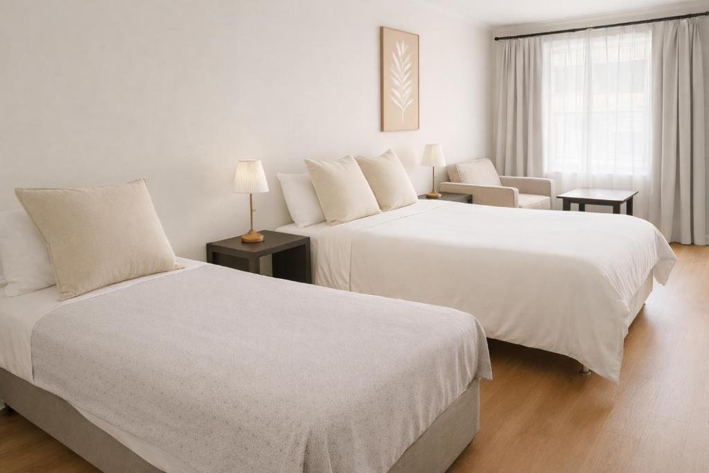 una stanza d'albergo con due letti e una sedia di Cooks Endeavour Motor Inn a Tweed Heads