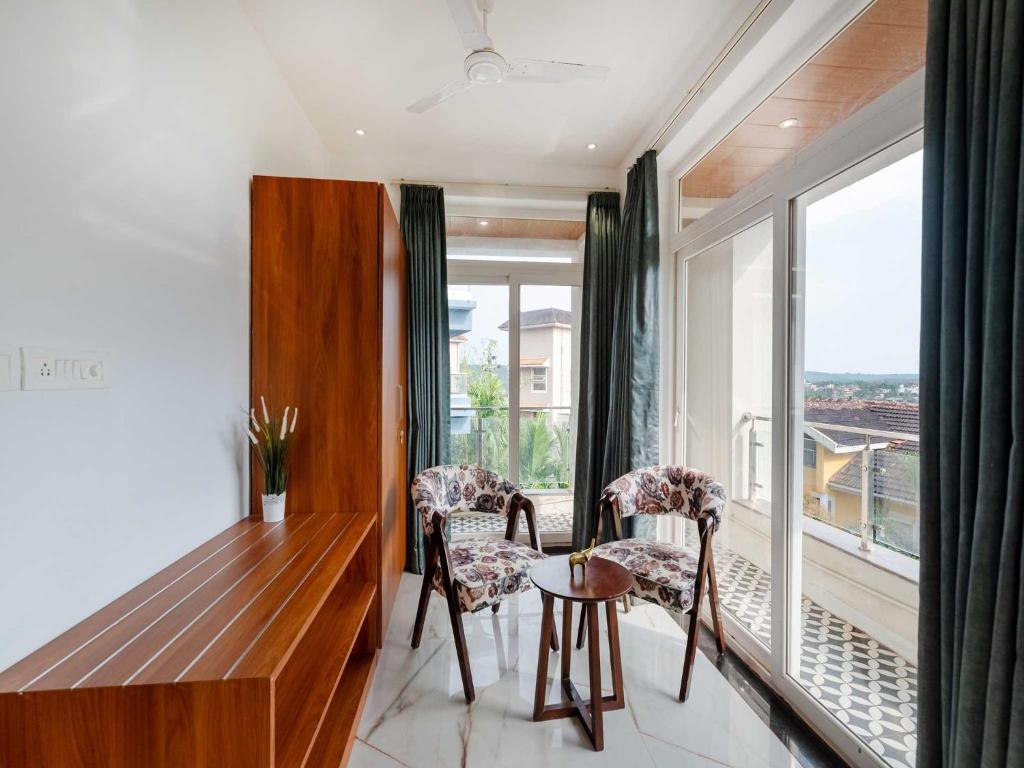 een eetkamer met een tafel en stoelen en een groot raam bij Villa Rouz By DanCenter | 5BHK | Pvt Pool | Baga Beach, GOA in Baga