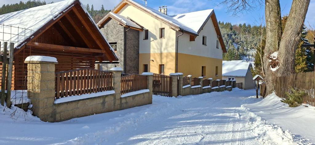 ein Haus mit einem Zaun im Schnee in der Unterkunft Vila Pohoda Javorníky s rozľahlým pozemkom in Makov