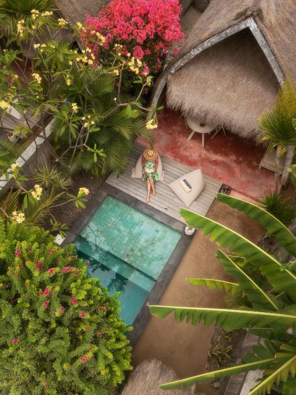 吉利美诺Villa Palma Gili Meno - Private Pool - Adult Only的从空中俯瞰,一名身穿比基尼的男子坐在泳池边。