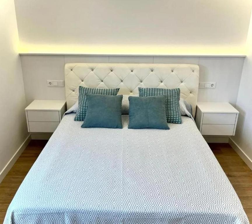 a bedroom with a large bed with blue pillows at Apartamentos Ézaro Beach in Dumbría
