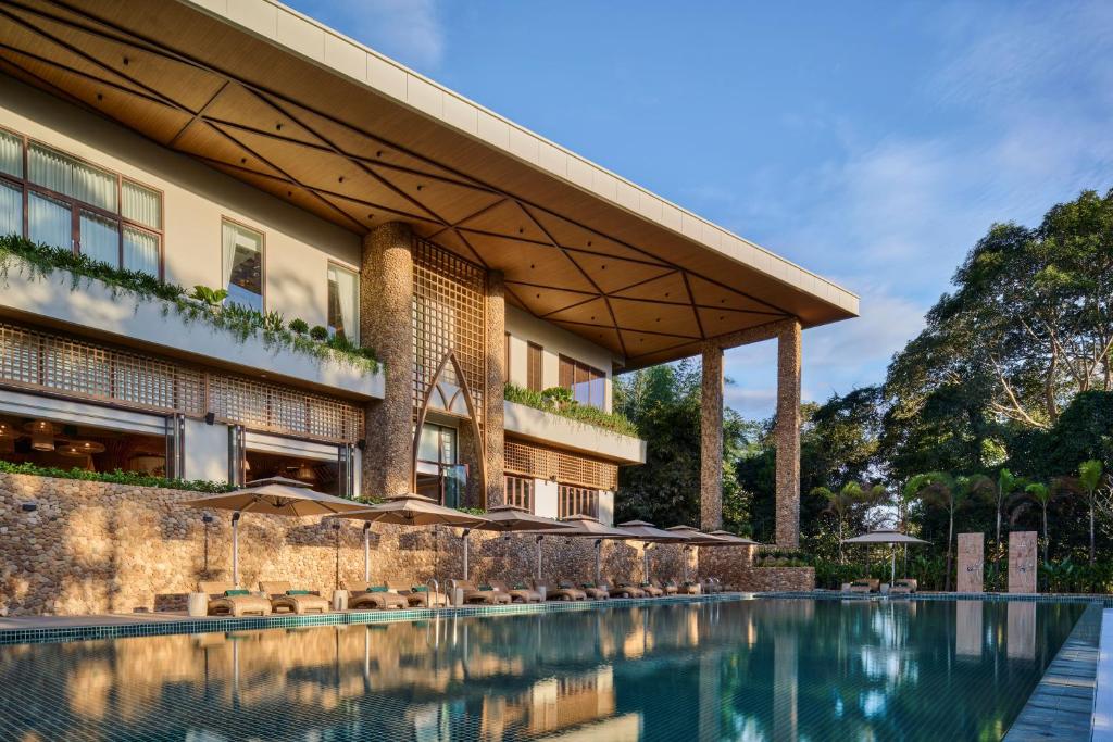 a hotel with a swimming pool in front of a building at Samanea Wellness Resort in Phumĭ Tŭk Lŭy