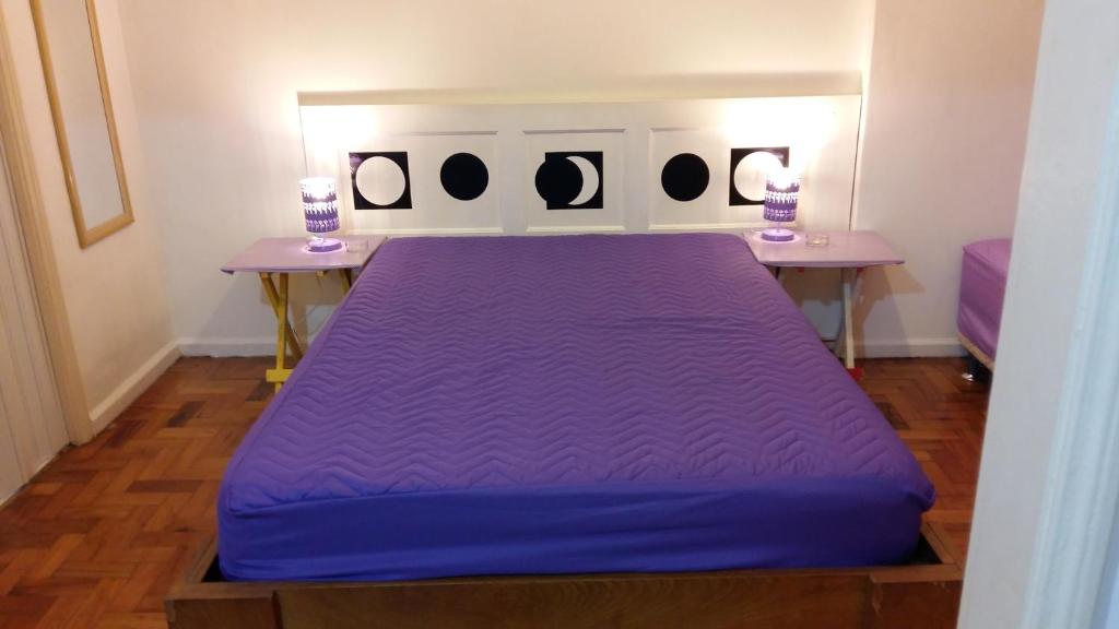 Cama morada en habitación con 2 mesas en Apartamento Lausanne, en Río de Janeiro