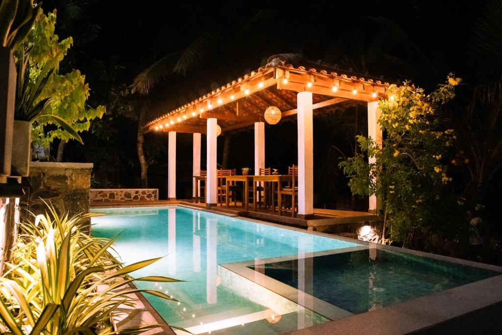 a swimming pool with a gazebo at night at Brown Birds Villa in Tangalle