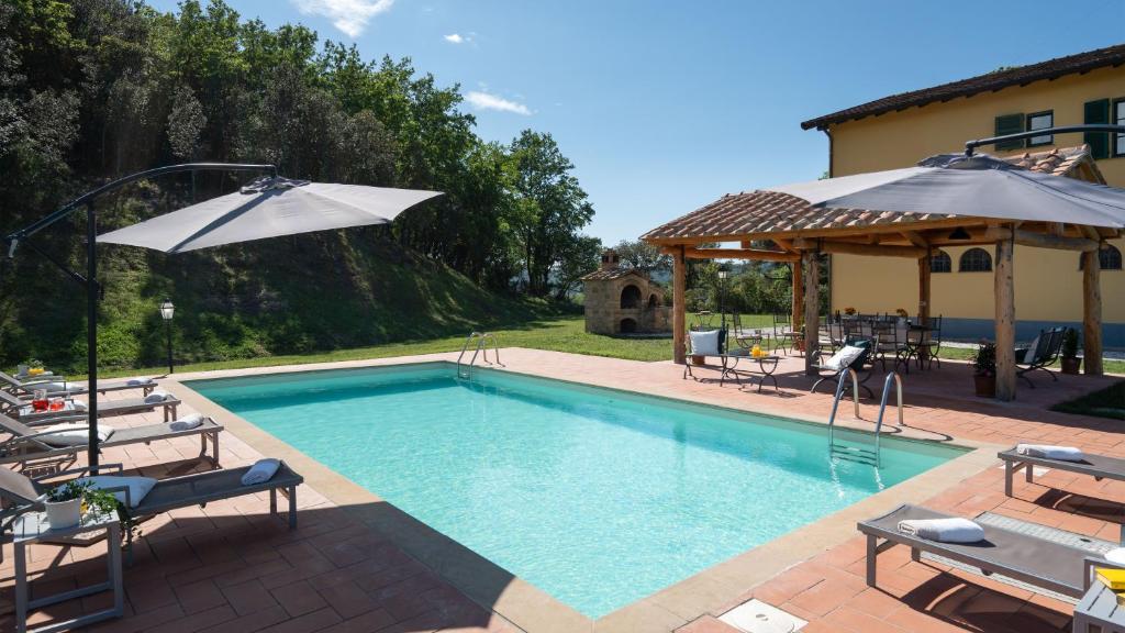 une piscine avec des chaises et un parasol dans l'établissement Podere Capanna - Il Tuo Rifugio di Relax nella Campagna Toscana, à Montecatini Val di Cecina 26 autres photos