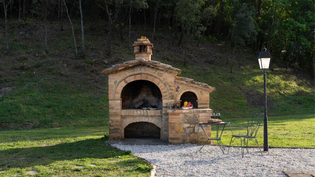 un four en pierre dans un champ avec une table dans l'établissement Podere Capanna - Il Tuo Rifugio di Relax nella Campagna Toscana, à Montecatini Val di Cecina