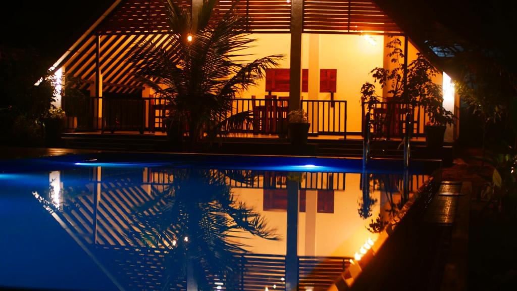 a house with a palm tree next to a swimming pool at night at Green Luxe in Dambulla