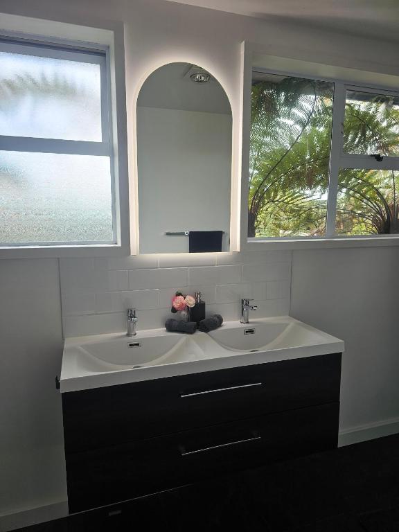 a bathroom with two sinks and two windows at Livingstone Retreat in Hokitika