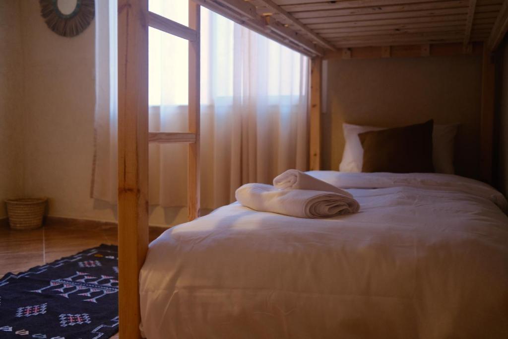 un letto con asciugamani in una camera da letto di Catamaran Surf House a Agadir nʼ Aït Sa