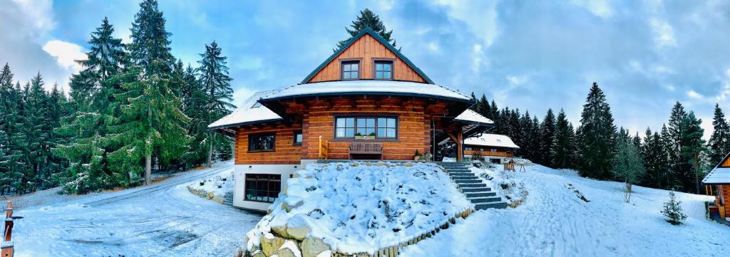 a large wooden building with snow on the ground at Drevenica Lesanka in Demanovska Dolina