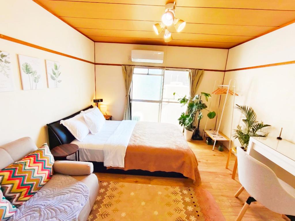een slaapkamer met een bed en een bank bij ゲストハウスDiDi in Tokushima