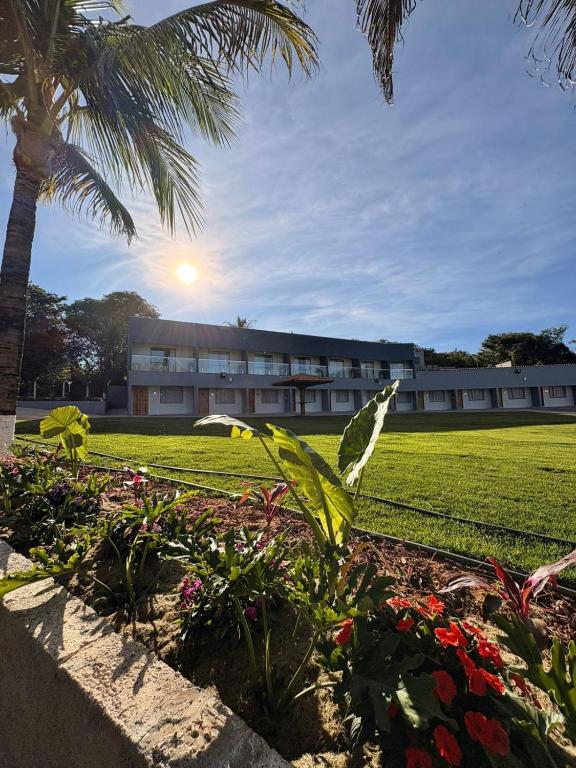 a building with a palm tree and some flowers at Hotel Castelo do Lago in Fama
