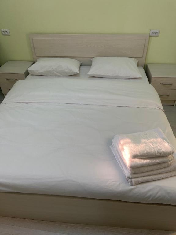 een wit bed met twee handdoeken erop bij Good Home in Jerevan