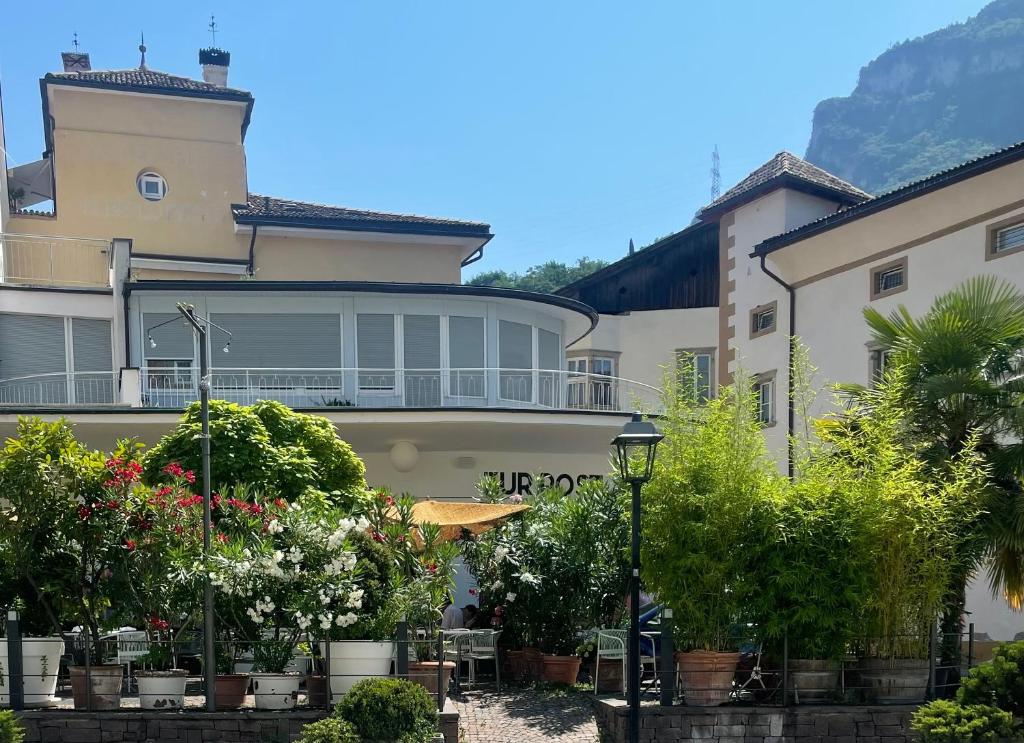 a building with a lot of plants in front of it at Hotel Zur Post in Egna