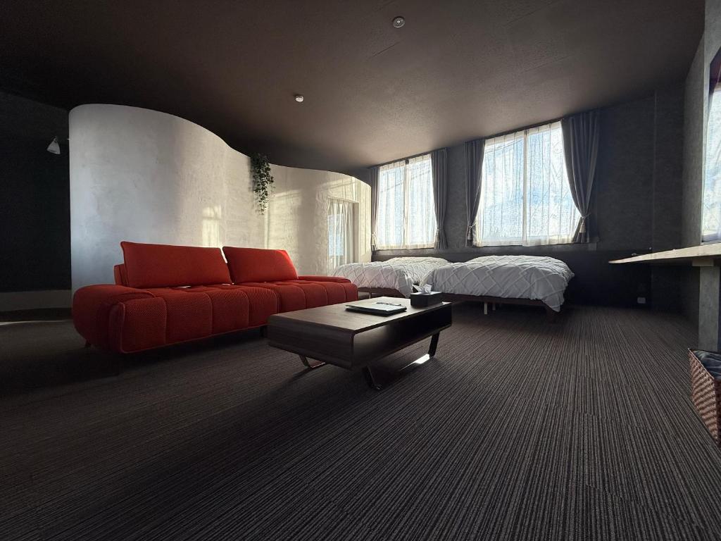 a living room with a red couch and a bed at 欒裏町ouchi uramachi in Matsumoto