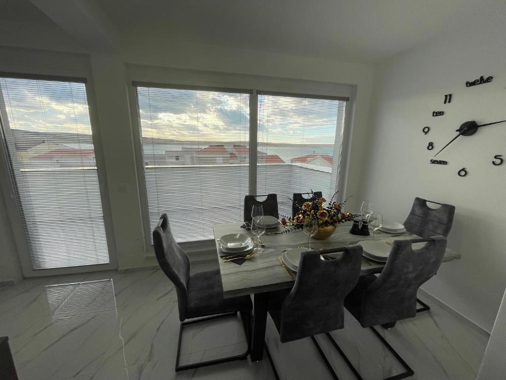 a dining room with a table and chairs and windows at Second home apartment - gold in Kustići
