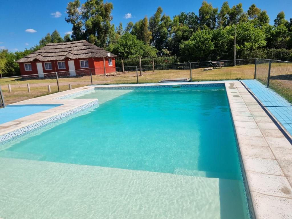 a swimming pool with a house in the background at Complejo Balcarce in San Rafael